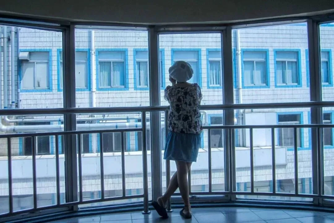 电子厂的女工去洗手间的间隙，站在楼梯间的窗台上发呆。