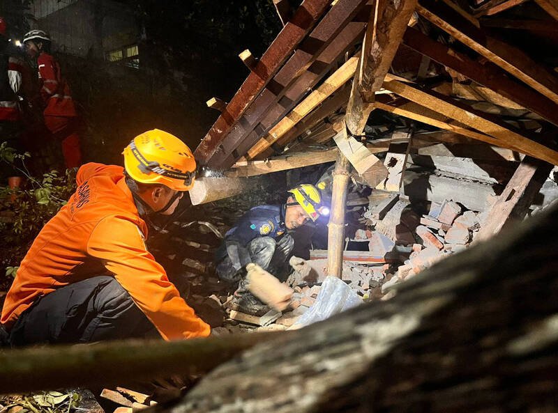 印尼爪哇岛近日因暴雨引发山崩，造成2人死亡和21人失踪。图为救援人员搜救画面。（美联社）