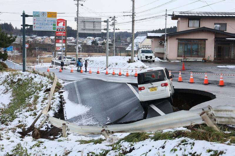 日本东北部外海8日深夜发生地震后，青森县一处道路地面塌陷，导致一辆车坠落。（法新社）