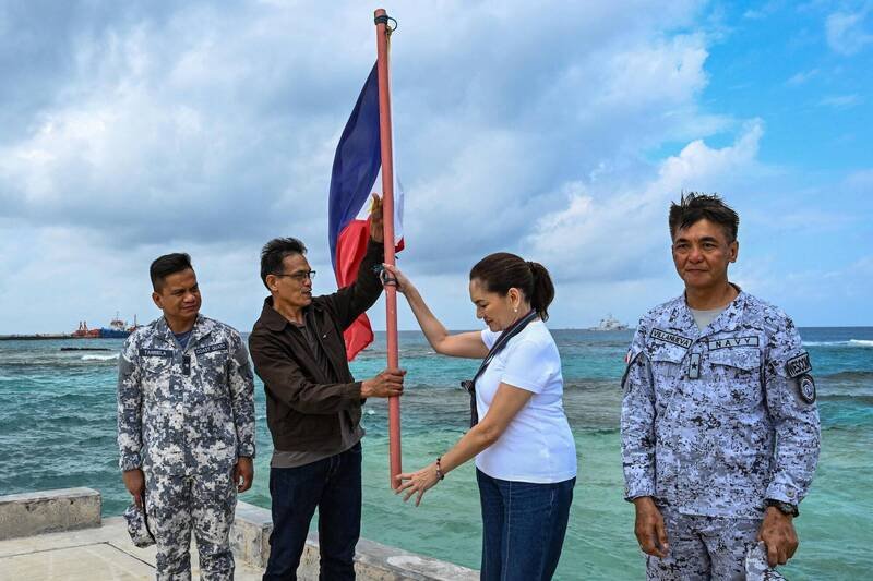 参议员洪迪薇（Risa Hontiveros，右二）和海岸防卫队、中业岛所属卡拉延市长和菲国海军将领21日在中业岛举起菲国国旗。（法新社）